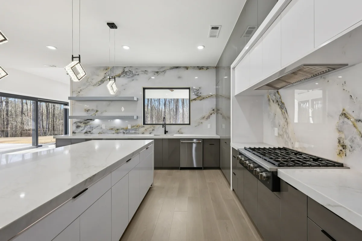 Kitchen with high-gloss dark grey upper cabinetry, a professional gas range, and a veined marble slab backsplash