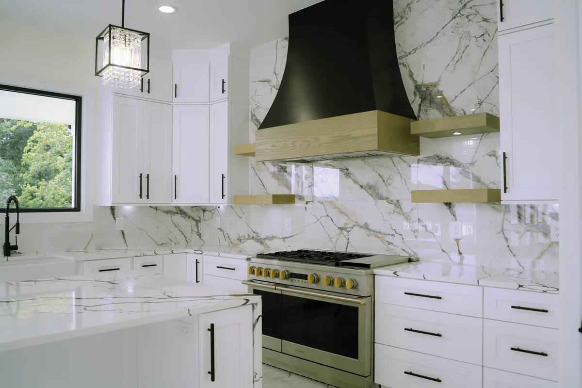 Cooking wall with a stainless gas range, a black hood, floating wood shelves, and a full-height marble-look slab backsplash