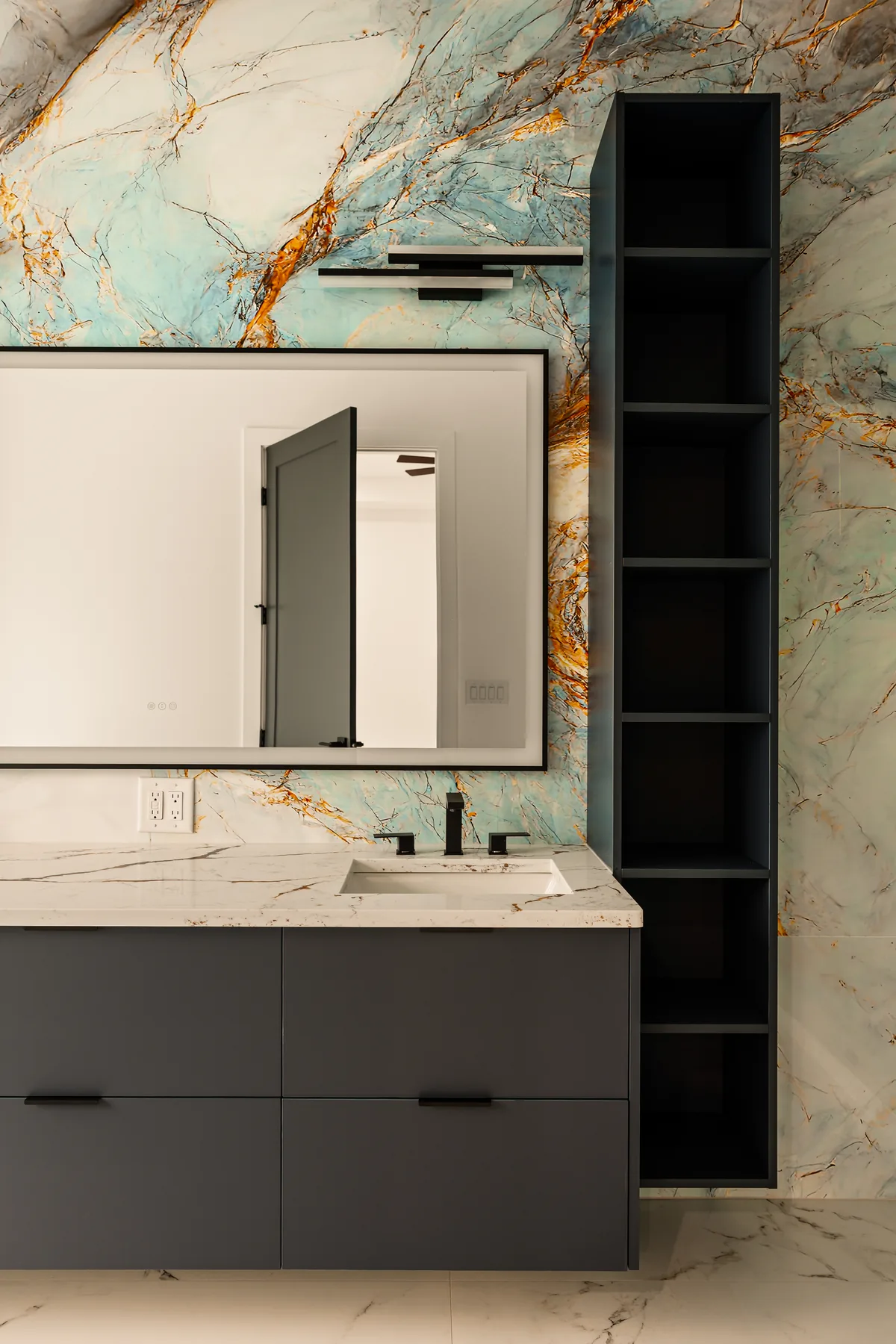 Bathroom vanity with a green quartzite slab backsplash, floating dark cabinetry, and a tall mirror