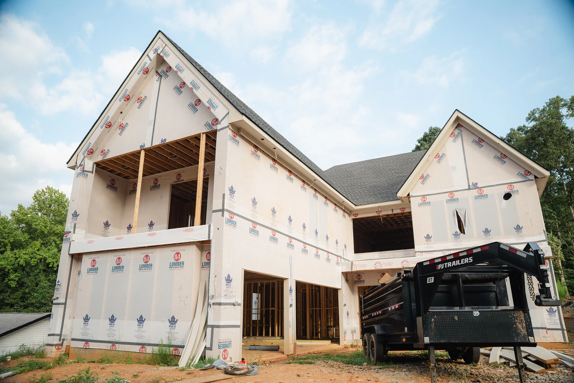 Two-story exterior with wrapped walls, open ground-level bays, and an unfinished upper opening.