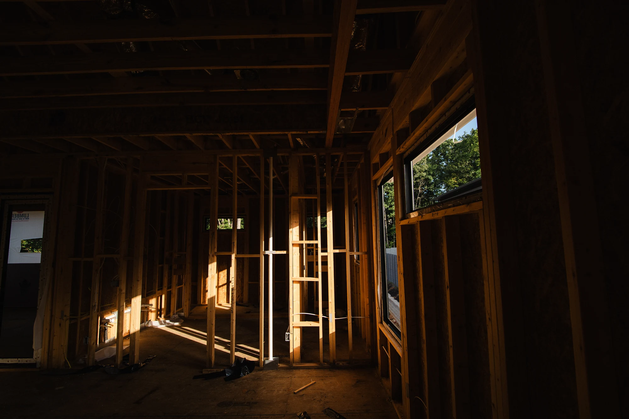 Dim framed interior with exposed studs, ceiling joists, temporary supports, and side windows.