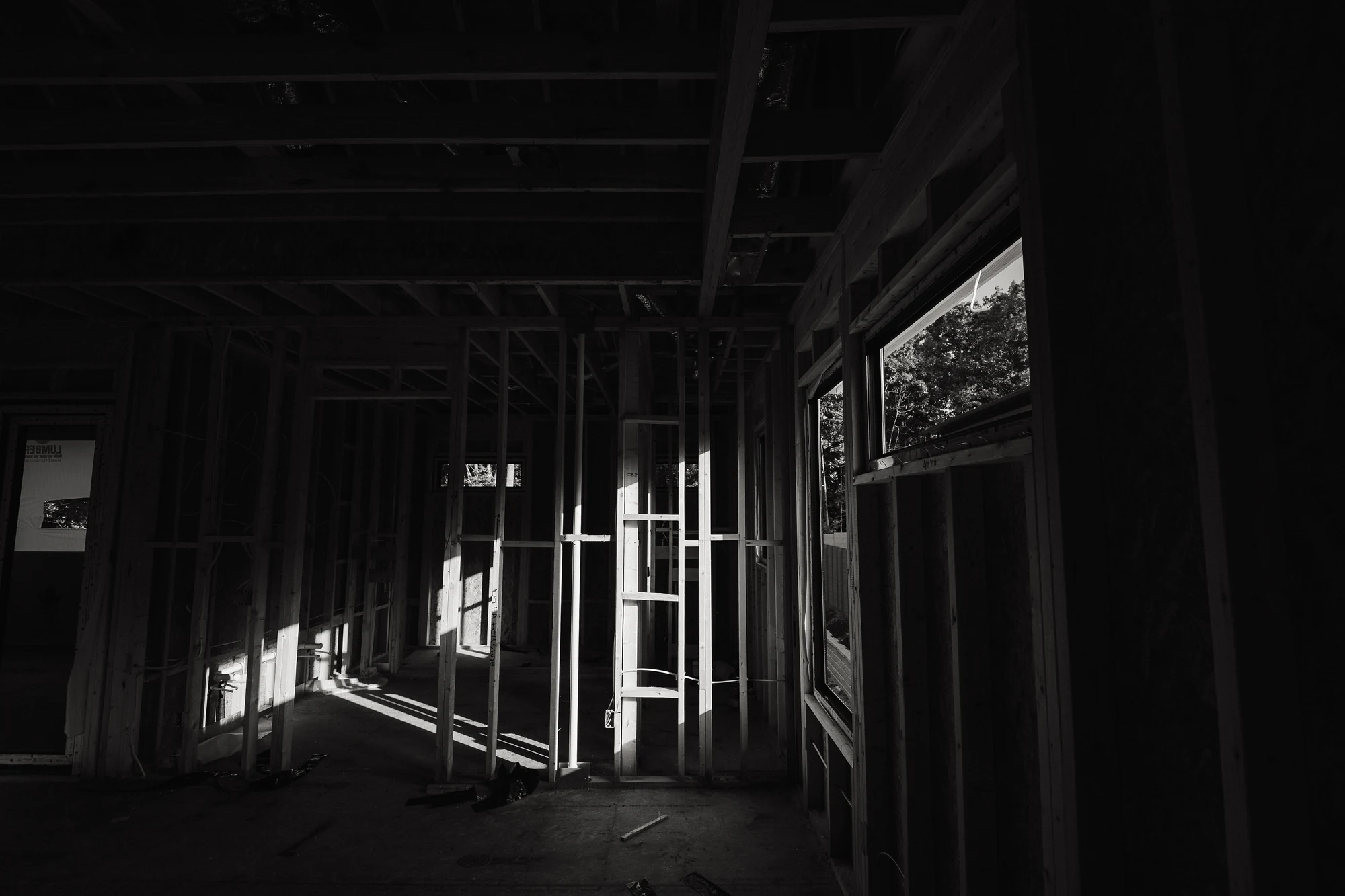 Black-and-white view of an open framed interior with temporary supports and window openings.
