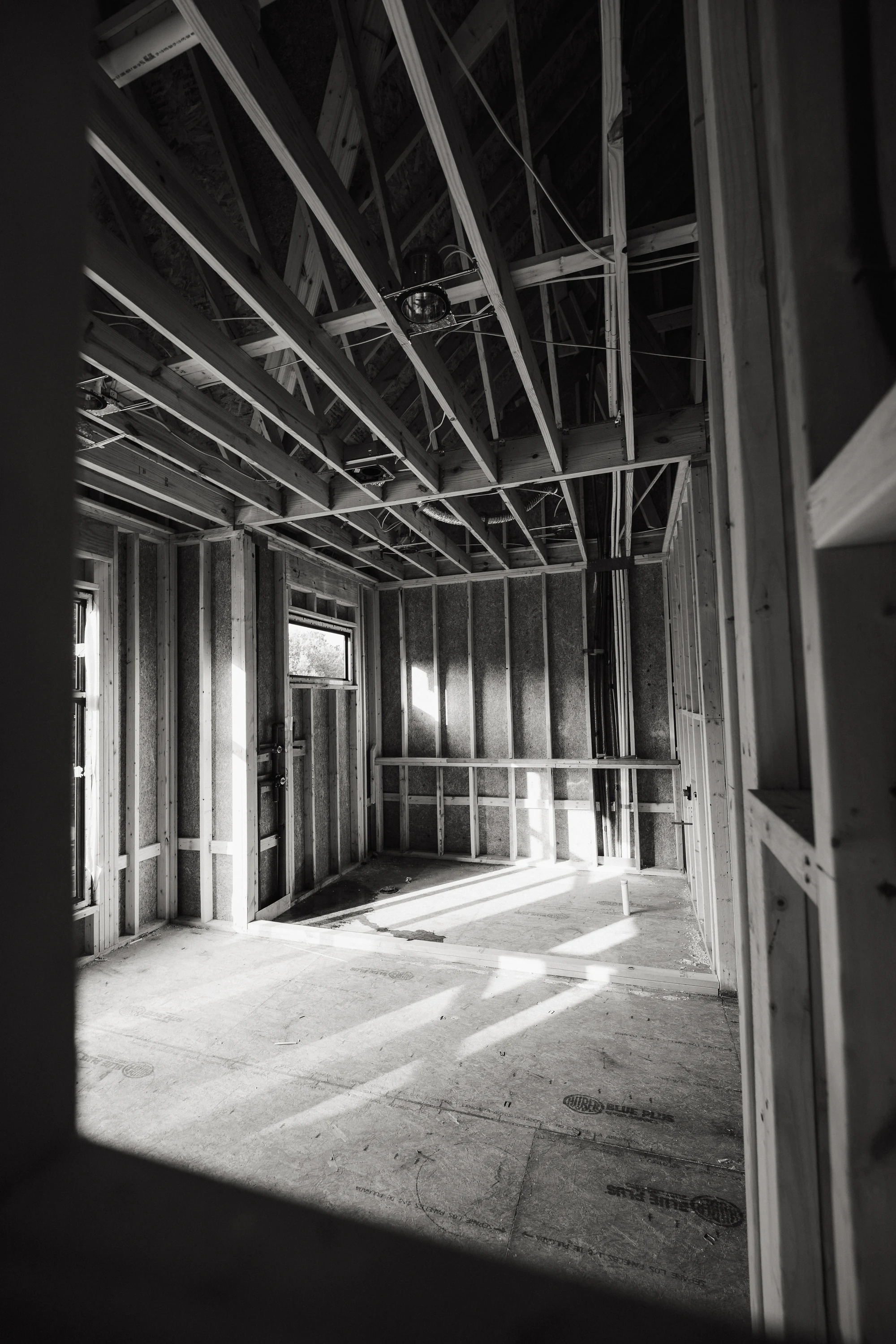 Black-and-white view of a framed interior alcove with ceiling joists and open wall cavities.
