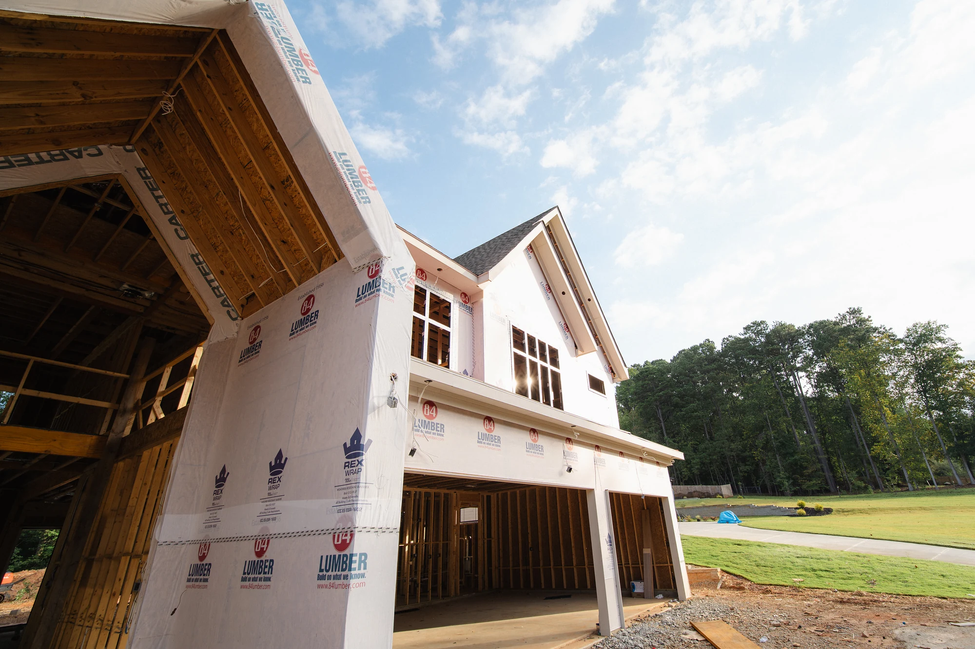 Low-angle corner view of a wrapped exterior with installed windows and an open lower-level bay.