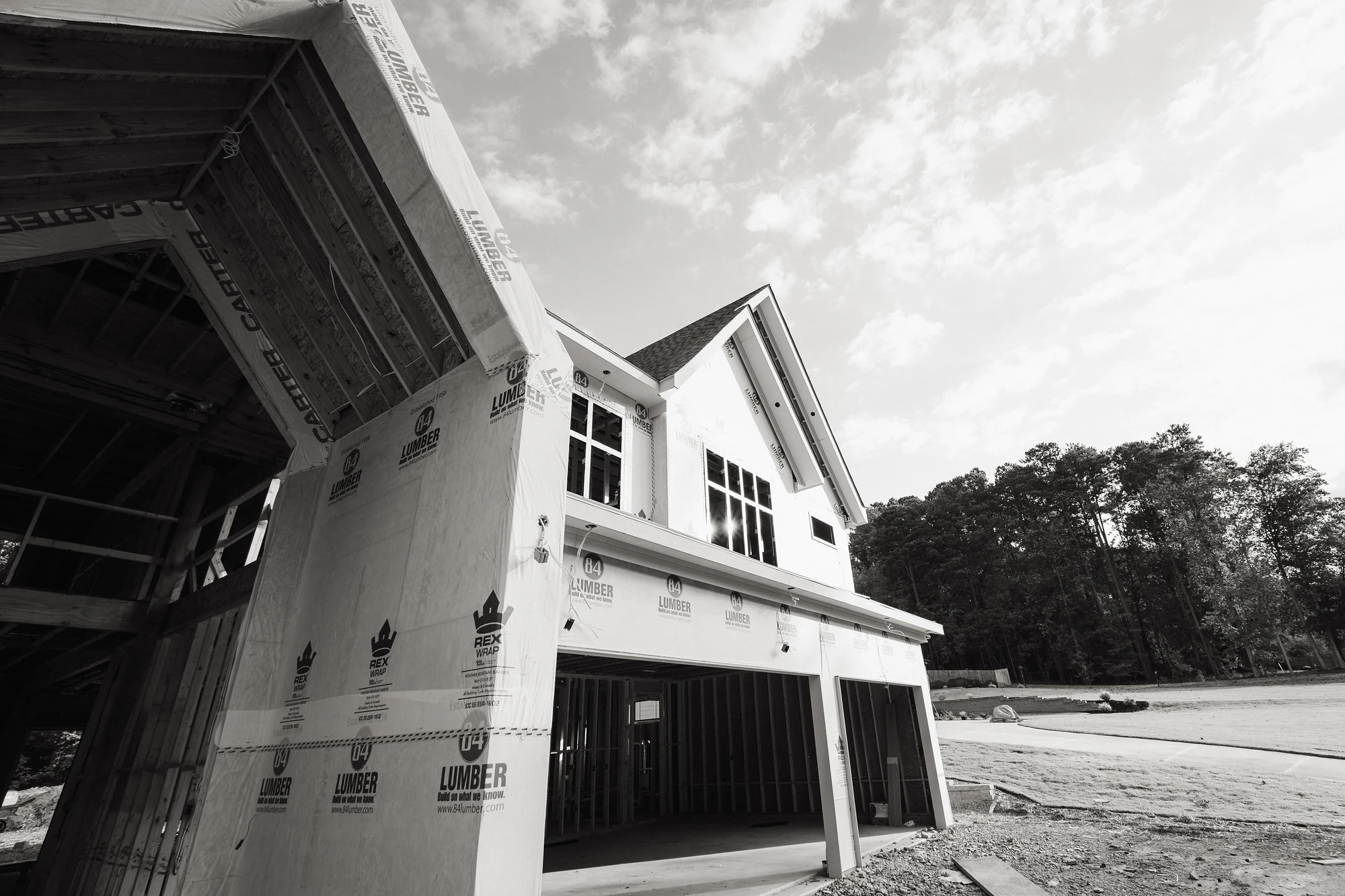 Black-and-white low-angle view of wrapped walls, installed windows, and an open lower bay.