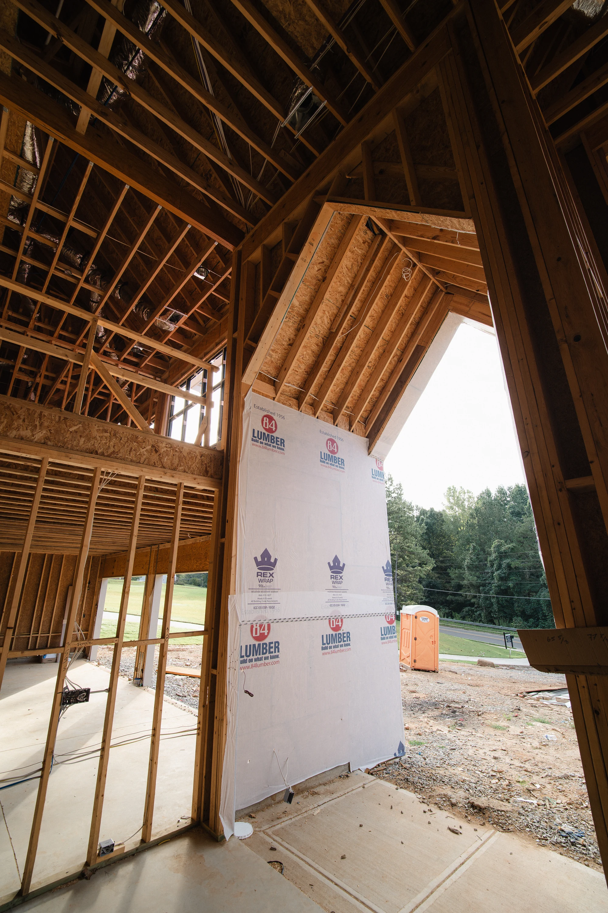 View beneath a framed exterior canopy beside wrapped walls and open wall framing.