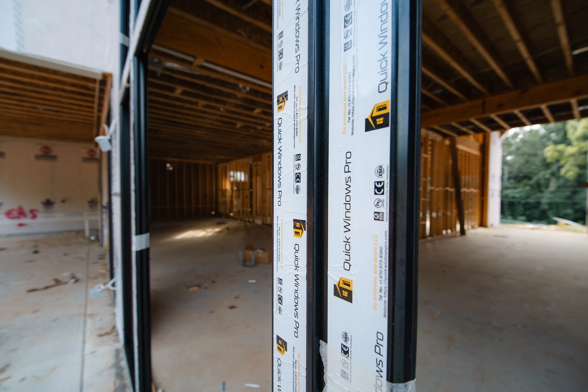 Close view through a newly set door frame into a large open framed interior.