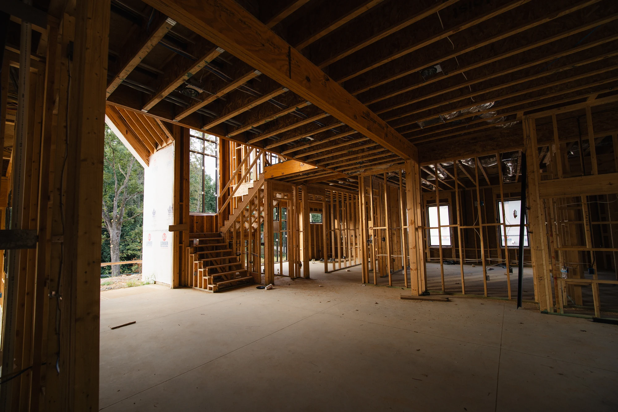 Open interior with concrete floor, exposed wood framing, and unfinished stairs in the background.