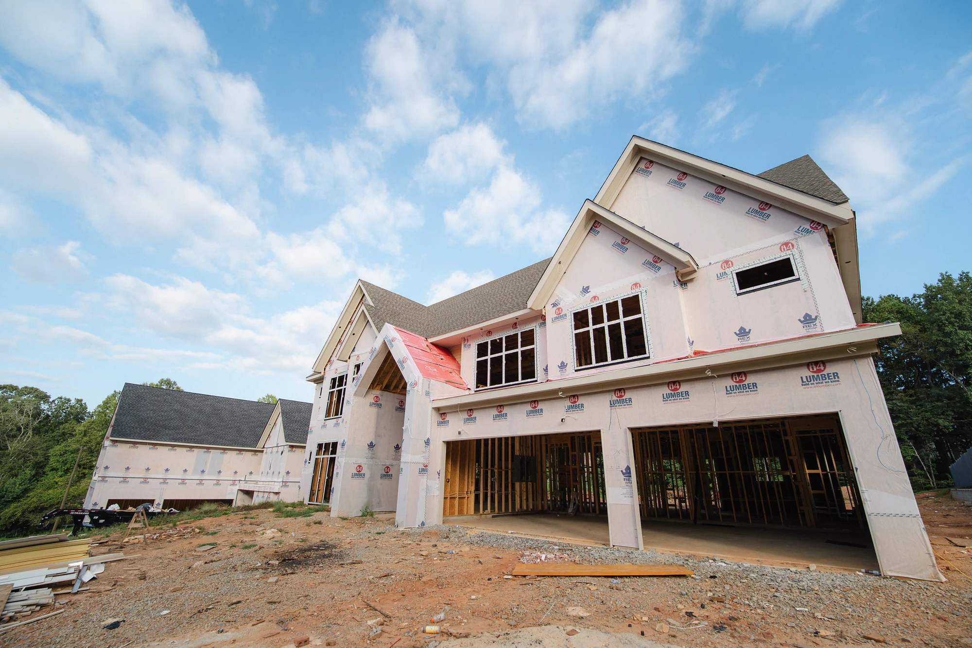 Low-angle exterior view of wrapped gables, installed windows, and two open ground-level bays.