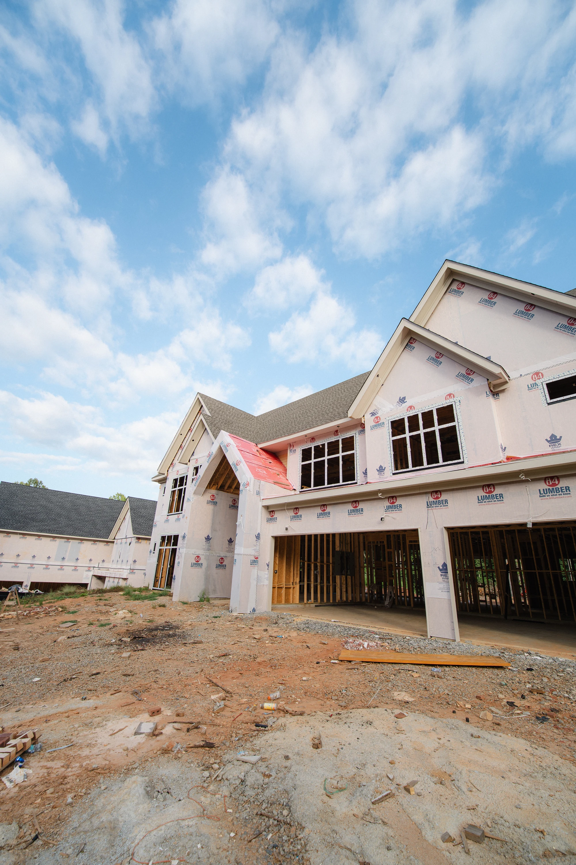 Closer exterior view of a multi-gabled facade with weather wrap, windows, and open lower bays.
