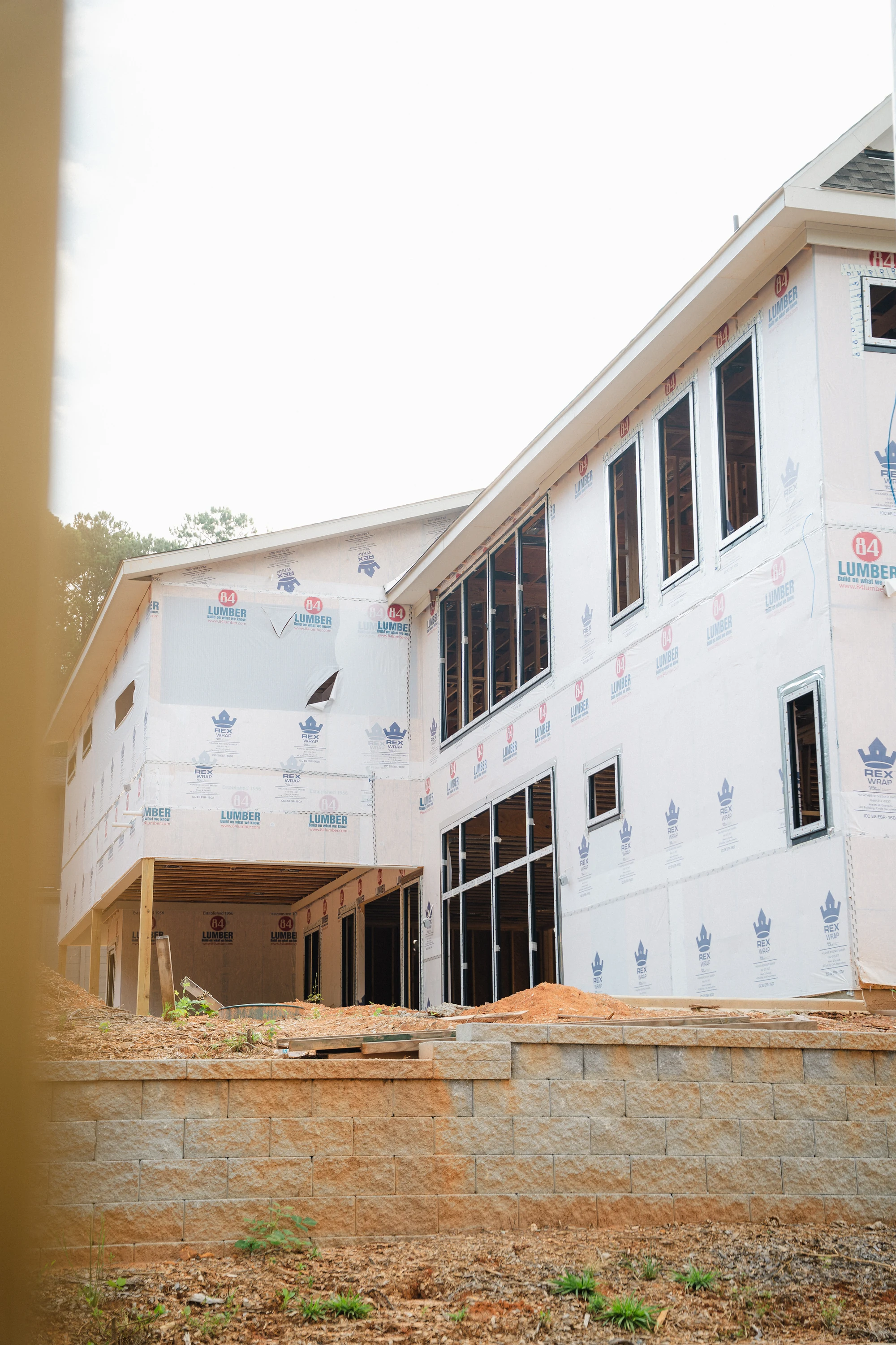 Tall side elevation with two rows of windows, weather-wrapped walls, and an open lower bay.