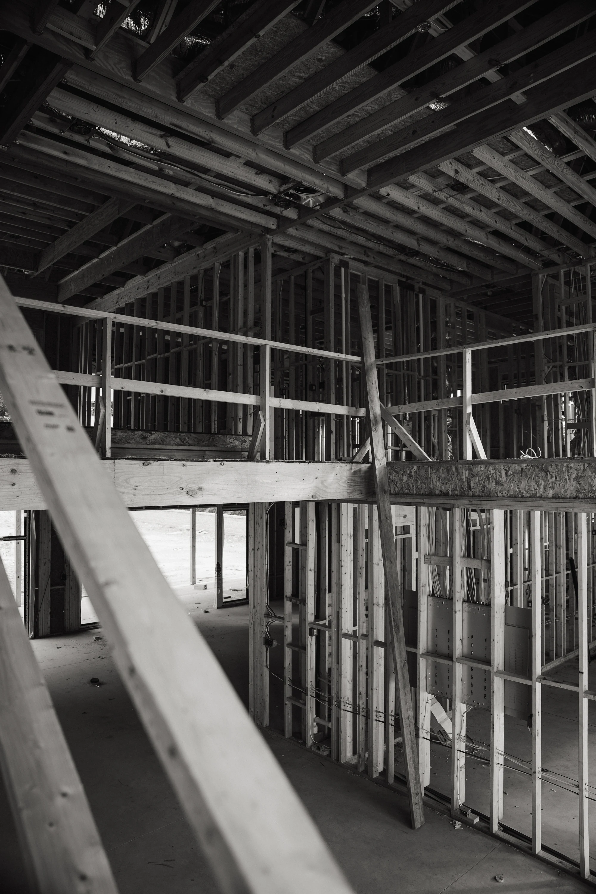 Black-and-white view of two-level interior framing with a diagonal temporary brace.