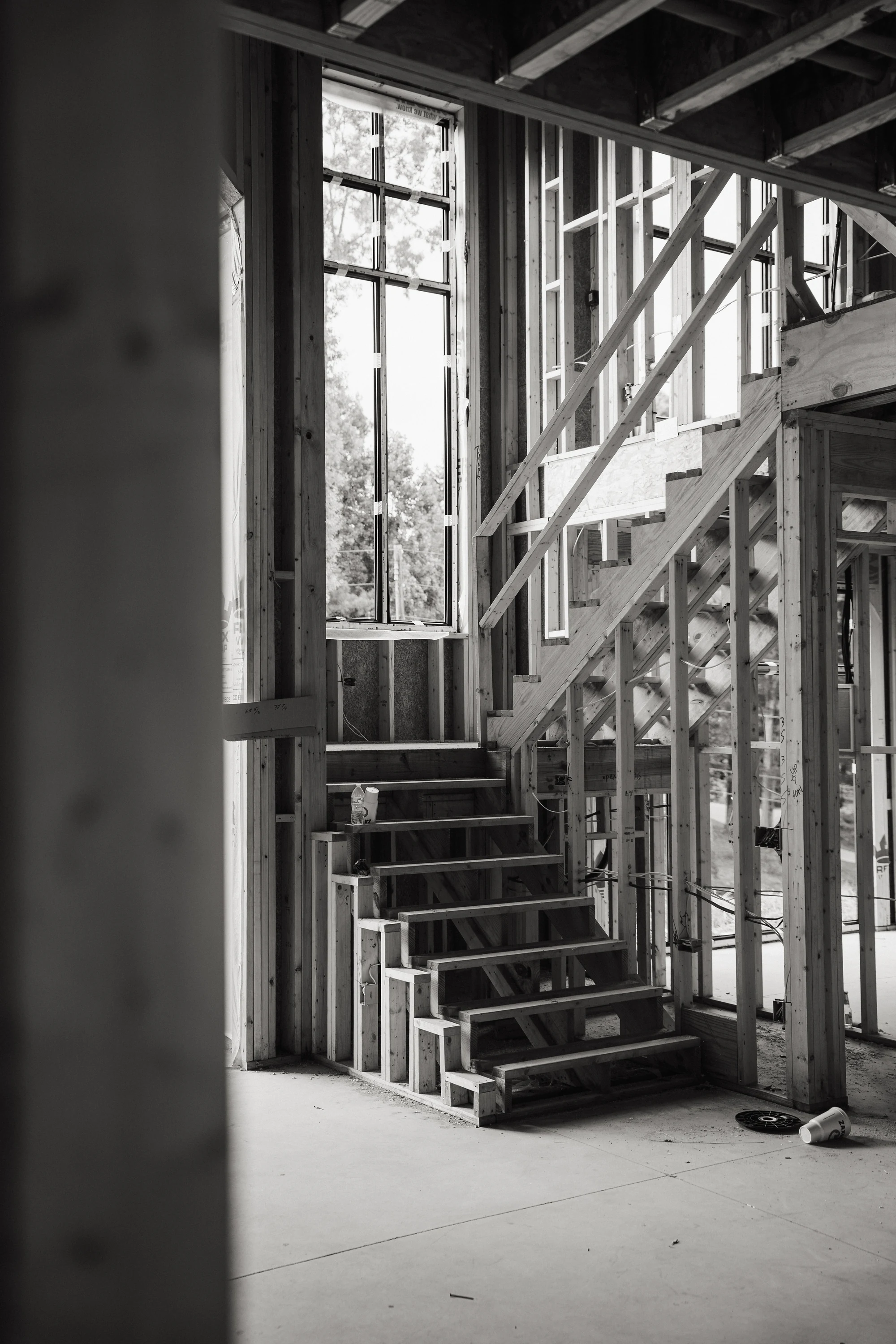 Black-and-white close view of unfinished stairs and surrounding wall framing.