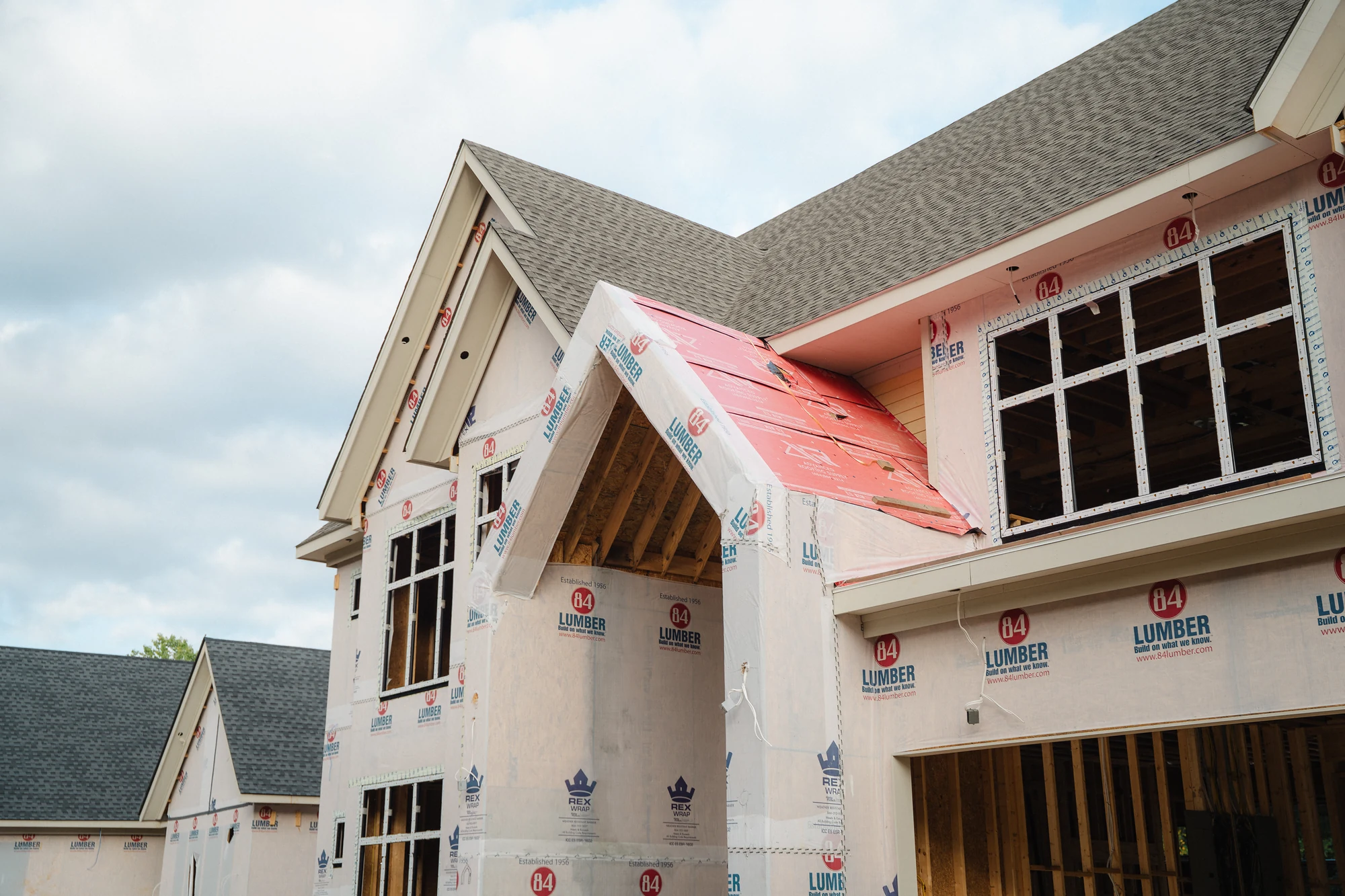 Closer exterior view of a wrapped gabled projection with exposed framing and adjacent windows.